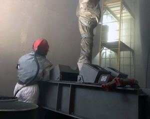 Photo of man in personal protective equipment applying a coating. Cover of the Coatings and Cathodic Protection Manual.