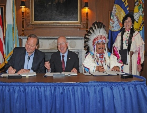 Photo of three men signing documents at a table