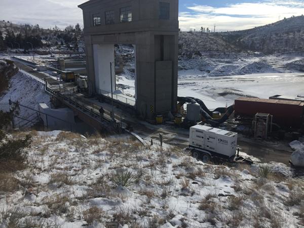Guernsey Spillway gatehouse with empty reservoir in background.