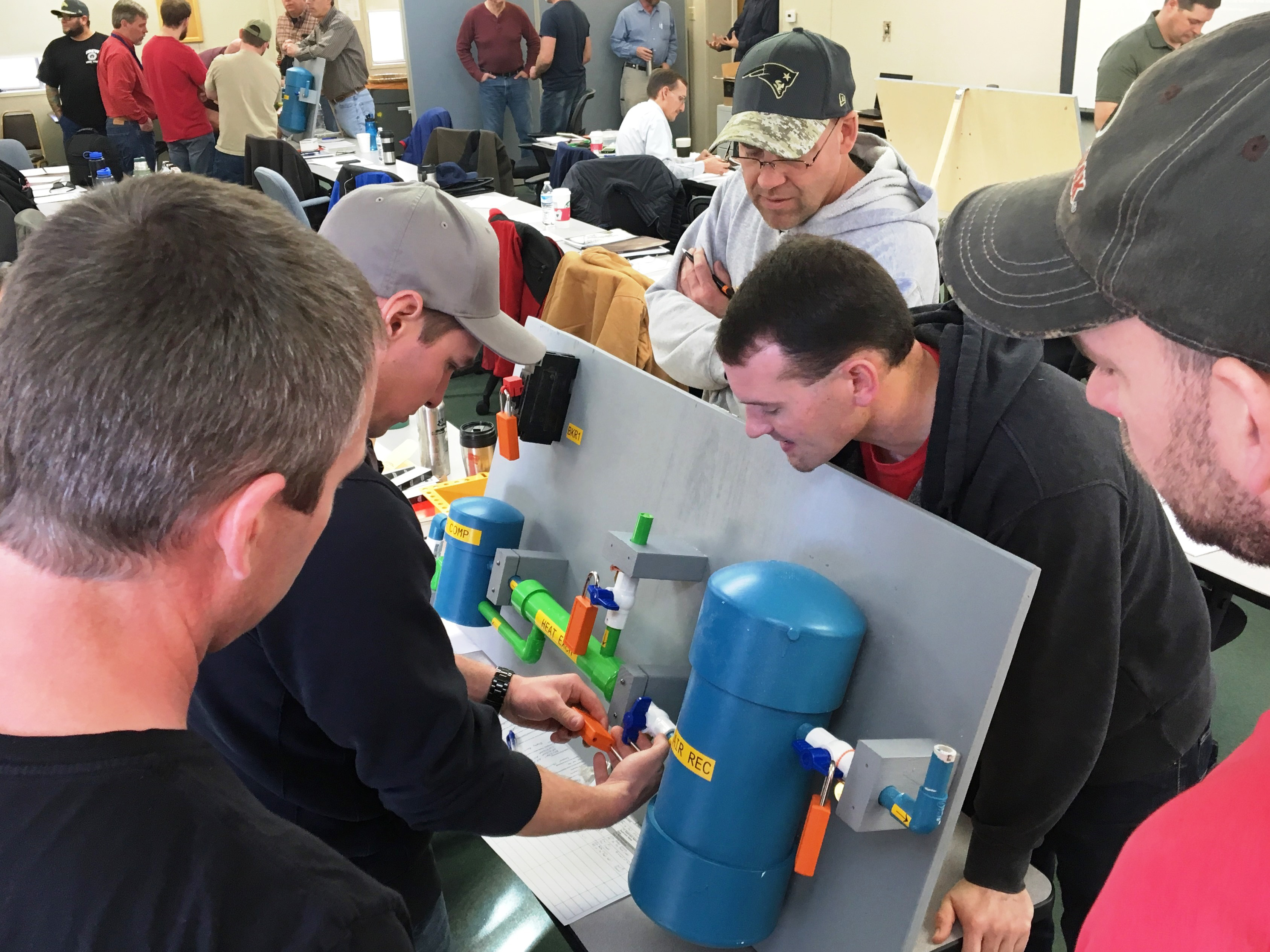Employees from the Flatiron & Estes Power Plants, Jonathan Haywood, Trent Cherry, Steve Jagielo, and Allan Philips watch as Adam Northrup applies a lock to the model.