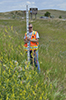 Jessica Voll, DKAO, wielding a digital level rod in the weeds at Heart Butte Dam, North Dakota. Photo by James E. Thornburg.