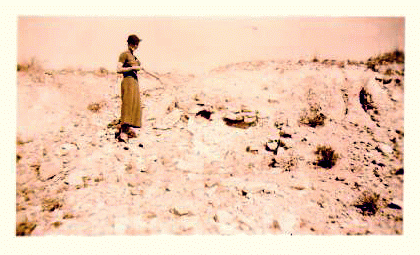 Woman standing on a hill side pointing out lime deposits. Sepia tone photo