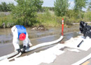Laying boom and pads to capture spilled oil where the flooding Yellowstone River is flowing onto Thiel Road. Image taken July 7, 2011.