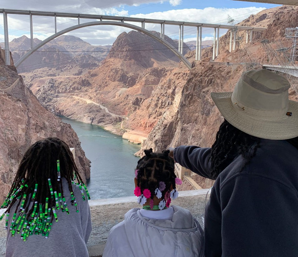 Two children and a tour guide look over Hoover Dam