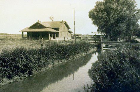 Farm home and irrigation lateral two miles west of Mesa, early 1900s. (Reclamation photograph)
