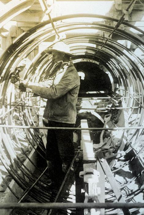 A hydropower plant provided electricity for the people building the dam and for running power equipment. Water for the generating units was brought via a diversion channel which crossed large drainages through a buried siphon.  Here a workman is preparing the rebar frame for a siphon across Pinto Creek, 1905. (Reclamation photograph)