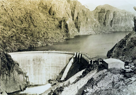 Constructed by the Salt River Valley Water User's Association between 1923 and 1925, Mormon Flat Dam was the first facility in the Association's privately-funded hydropower expansion program. It was built for the dual purposes of generating hydroelectric power and for storing approximately 57,000 acre-feet of water in its reservoir, Canyon Lake, for agricultural and urban/commercial uses in the Salt River Valley.   In a radical departure from the design used by the U. S. Reclamation Service for Roosevelt Dam, C.C. Cragin designed a concrete, thin-arch structure with a height (streambed to crest) of 224 feet.  The dam's crest is 380 feet long, with a top width of 8 feet and a maximum base width of 20 feet. (SRP photograph)