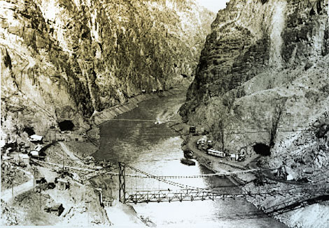 This view of the Black Canyon damsite looking downstream shows preliminary work preparing the site for construction.  The two tunnels can be seen that will divert water around the construction site. (Reclamation photograph)