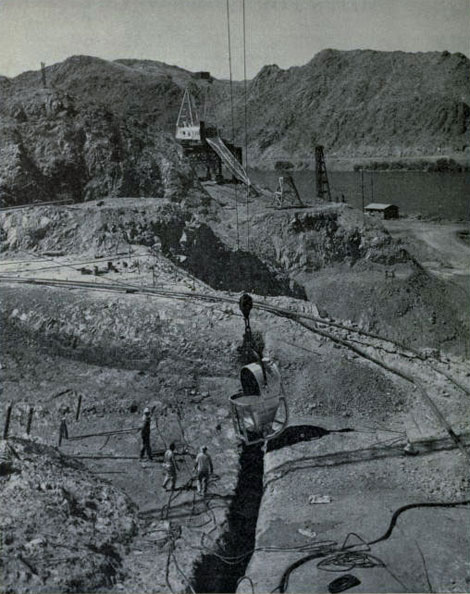 Progress at Davis Dam. Here is the first bucket of concrete being poured into the gravity wall foundation cut-off trench at Davis Dam in Ariz.-Nev. The main purpose of Davis Dam is to generate electrical energy and to reregulate the Colorado River, below Hoover Dam, through the provision of storage for irrigation and domestic use within the United States and for the delivery of water at the U.S.-Mexico international boundary. Reclamation Photo.