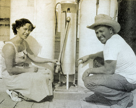 Proud of their water purifier are Mr. and Mrs. Gerald L. Didier as they point to part of the water system that they have installed on their homestead on the Yuma Mesa Division, Gila project. The system includes the water softener to Mr. Didier's right, the germicidal lamp purifier in the middle, and the automatic water heater to Mrs. Didier's left. Photo by M. N. Langley of the bureau's Region 3.