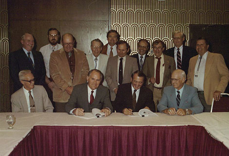 Signing of the first CAP water delivery subcontract between the Harquahala Valley Irrigation District (HVID), the Central Arizona Water Conservation District (CAWCD) and the Bureau of Reclamation (Reclamation) was a milestone event in project history. Seated, left to right – Burr Sutter, CAWCD Counsel; Dale Shumway, CAWCD Board President; Bill Plummer, Regional Director, Reclamation; Lynn Sharpe, CAWCD Secretary. Standing, left to right – Dess Chappelear, Asst. Project Manager, Arizona Projects Office, Reclamation; Tom Koenekamp, Franzoy, Corey & Associates; Frank Rogers, President, HVID; Jack Williams, CAWCD Board; Fred Corey, Franzoy, Corey, and Assoc.; W. T. Gladden, HVID Board Director; LeGrande Neilson, Reclamation, Contracts and Repayment; Bob Farrer, Vice President, Franzoy, Corey & Assoc.; Jim Green, HVID Counsel; Harry Porterfield, HVID Secretary.Photo courtesy of HVID.