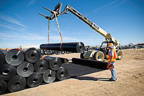 1,700 rolls of geomembrane lining, each weighing more than a ton, stand by for installation in the excavated reservoir area.