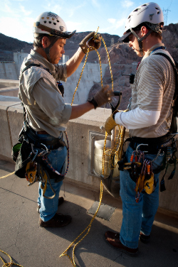 Rodney Tang, left, and Rich Eastland, prepare their equipment in advance of descending over the top of the dam.