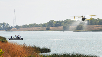 Plane flies over a vessel in a water-filled channel.
