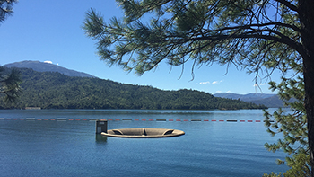 The top of the Whiskeytown Dam’s glory hole spillway is visible above the reservoir’s placid surface.
