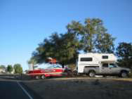 non-interactive image of a pickup with a camper hooked to a boat