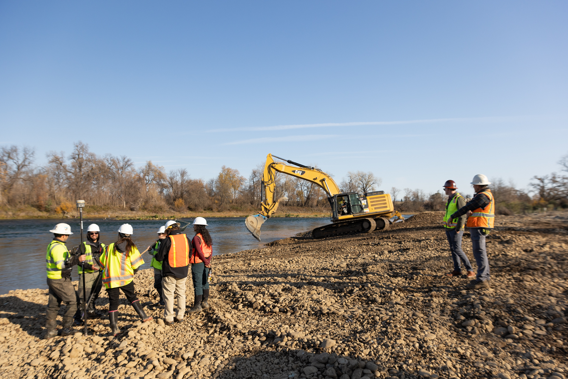Crews carving a side river channel and reshaping the main riverbed with gravel for juvenile fish