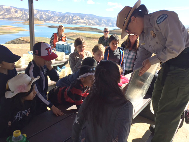 A park ranger shows students a poster on the water cycle.