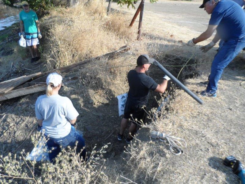 Volunteers lift trash out of ditch near Steel Canyon.