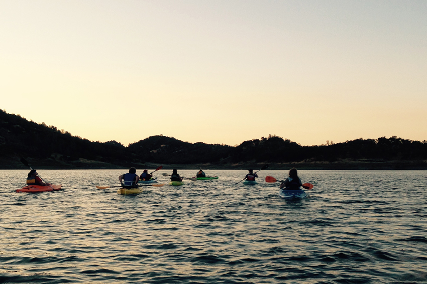 Sun setting while kayakers on the water at Lake Berryessa