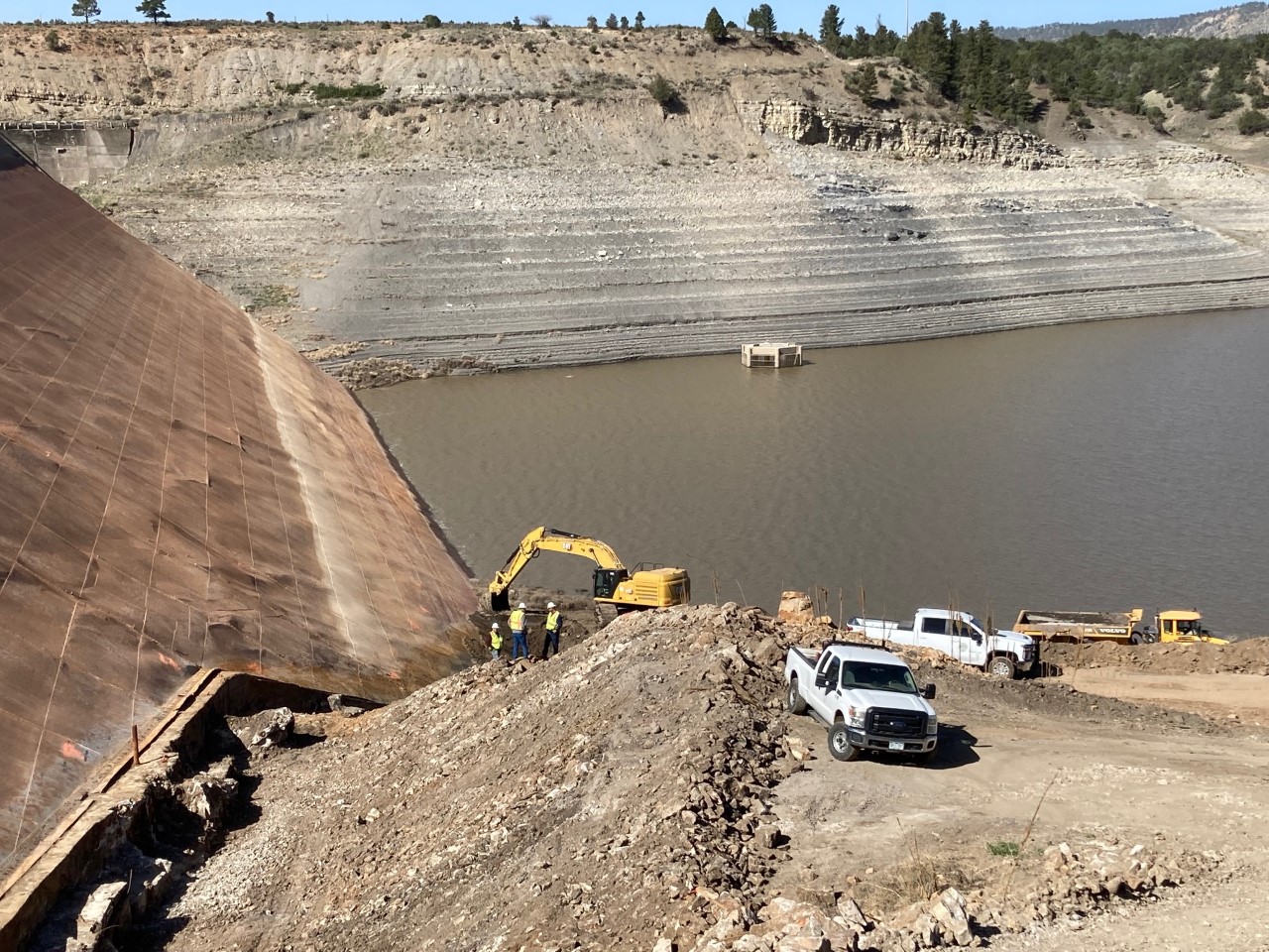 Excavator cutting away sediment sludge long dam steel plates