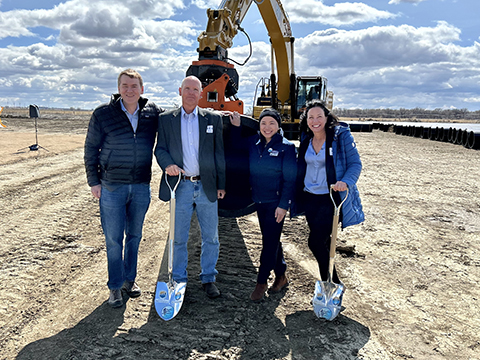 Four people standing in front of an excavator.