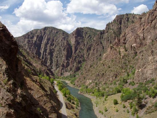 The Gunnison River running between large cliffs and a blue sky.