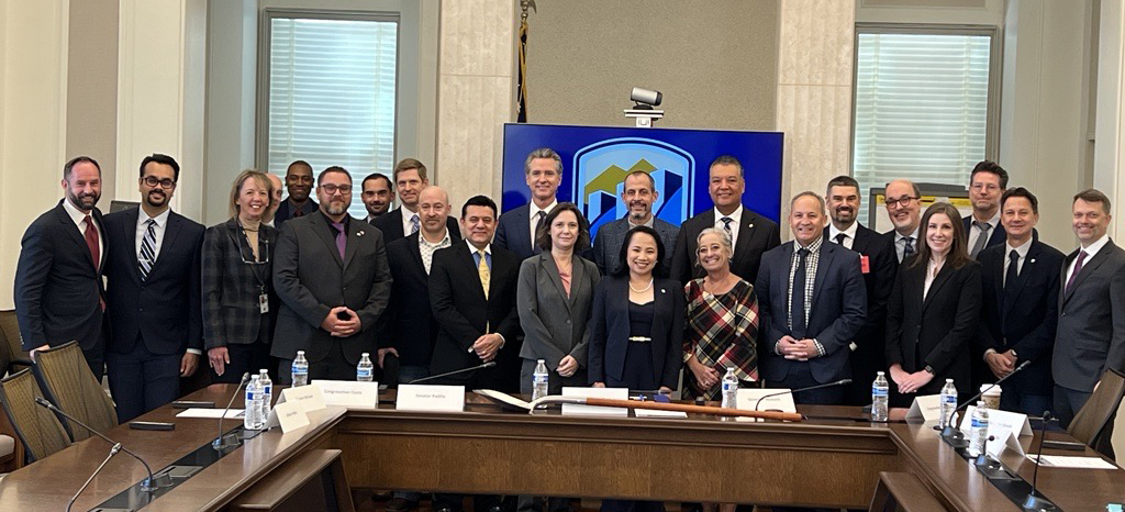 A group of people standing behind a desk after signing a document.