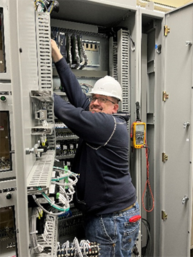 electrician Carl Jason Latham works in an electrical cabinet at Blue Mesa Power Plant