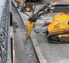Using a skid steer with a Jack Hammer attachment to break up hardened grout.