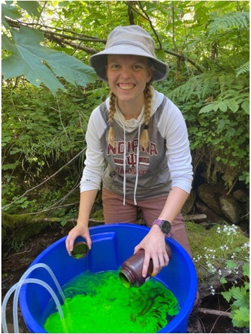 Paige Becker pouring dye into a large plastic bucket