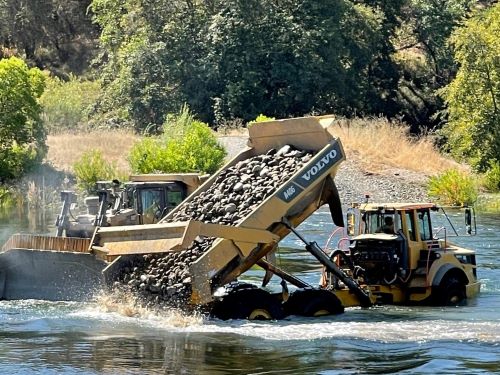 truck placing rock into river