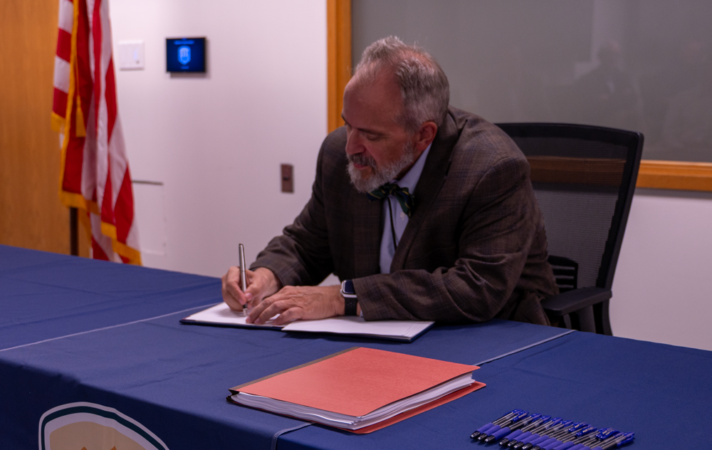 Regional Director Wayne Pullan adds the last signature to the contract