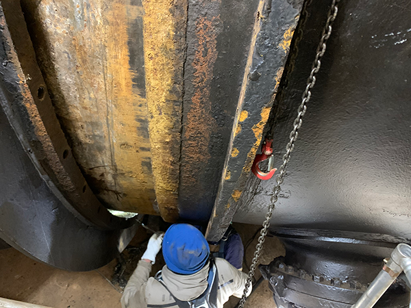 Plant mechanic Gregg Goss reaches into the small space between the flange and the penstock to remove the old rubber packing, which had become brittle and was no longer creating a water-tight seal.  