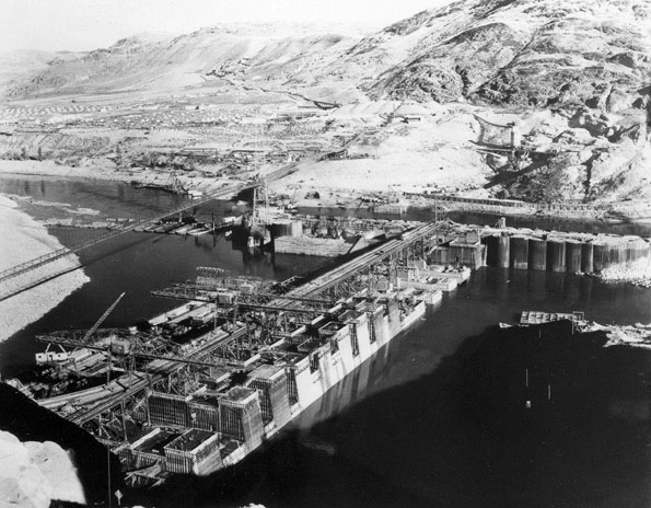 Photo taken November 20, 1936. Looking north east over west side high and low crane trestles, note the cantilever cranes, at Grand Coulee Dam.