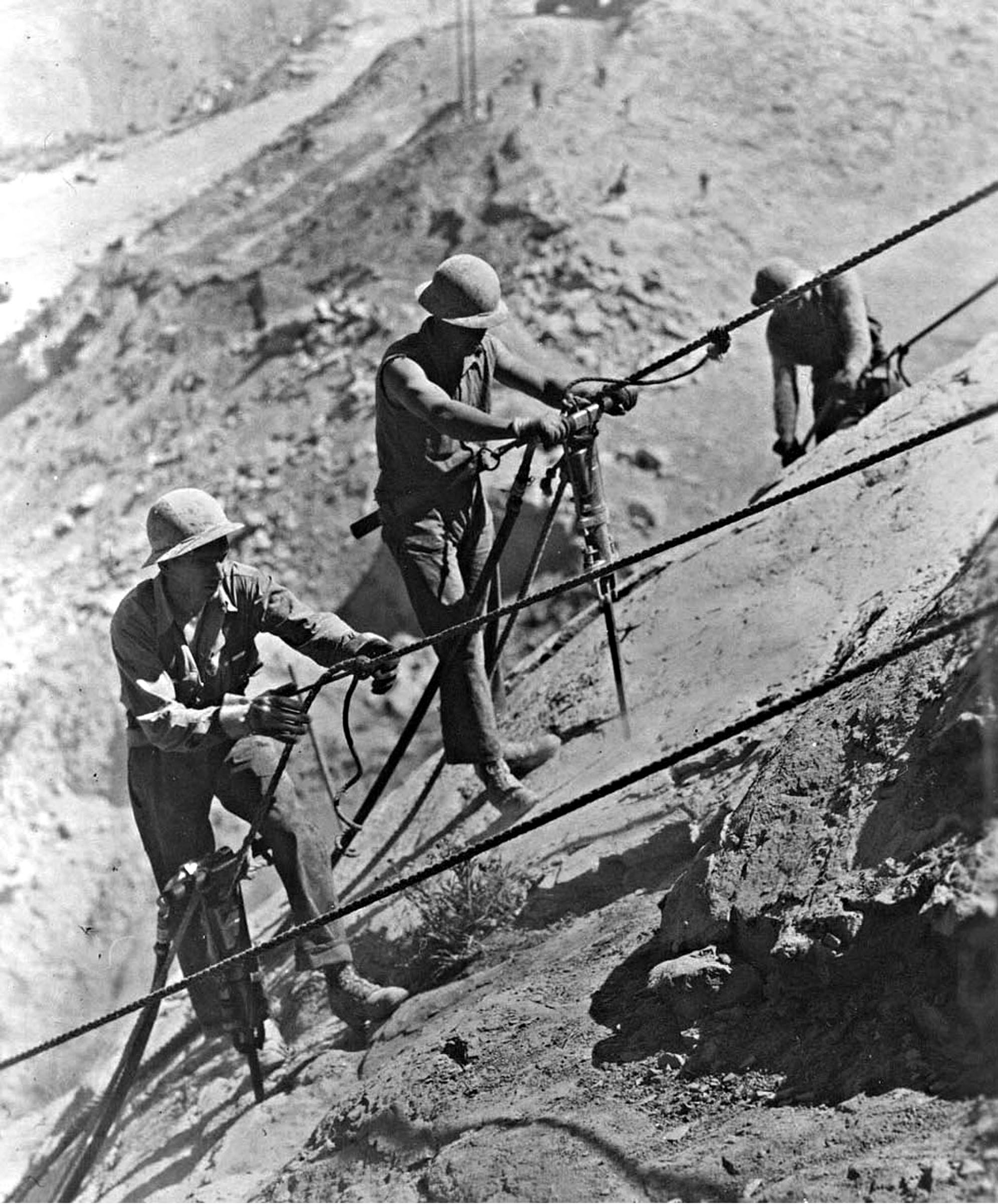 Photo taken Circa 1938. Drilling blasting holes in rock face for Grand Coulee Dam.