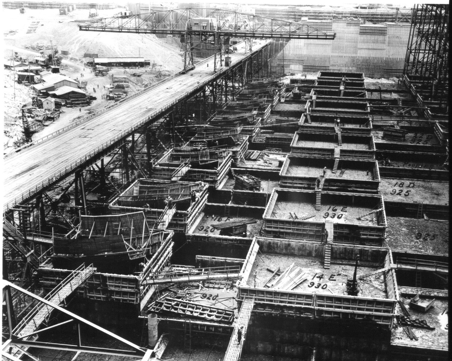 June 26, 1936. Cantilever crane on low crane trestle for placing concrete in foundation forms at Grand Coulee Dam.