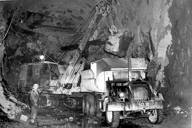 Guy F. Atkinson Company equipment excavating material for the 36' diameter diversion tunnel at Hungry Horse damsite. The 1 1/2-yard electric shovel loads a 20-yard truck. March 26, 1948.