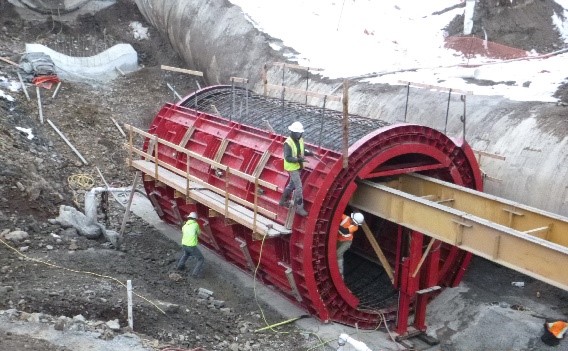 Crews use a red steel form to pour concrete to construct the Warden Siphon.