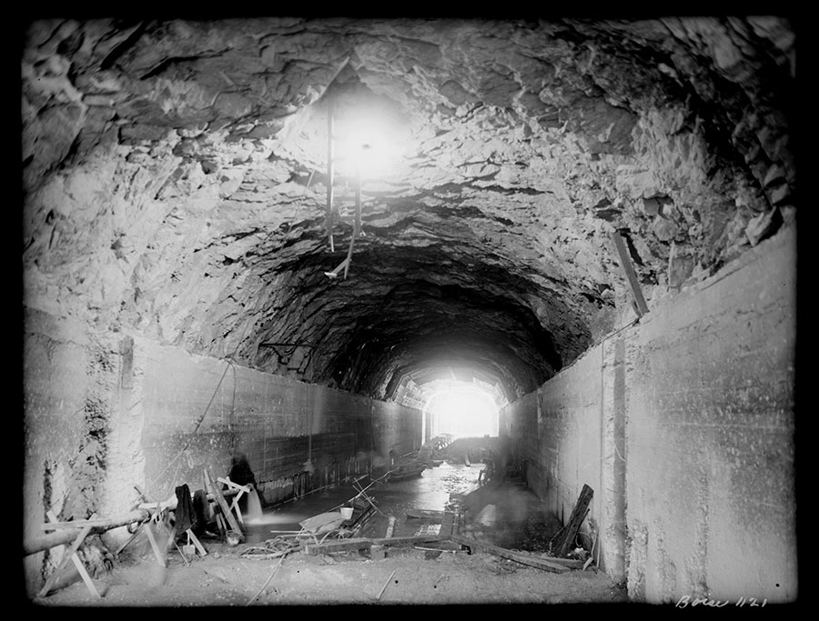 Arrowrock dam site. Diversion tunnel looking downstream. Timbering and timber lining of area, though section under dams, has been removed and this section is being cleaned up preparatory to filling with concrete. Upstream key in side lining shows above foreground. One of the three shafts for filling from inspection gallery shows indistinctly at top of picture.