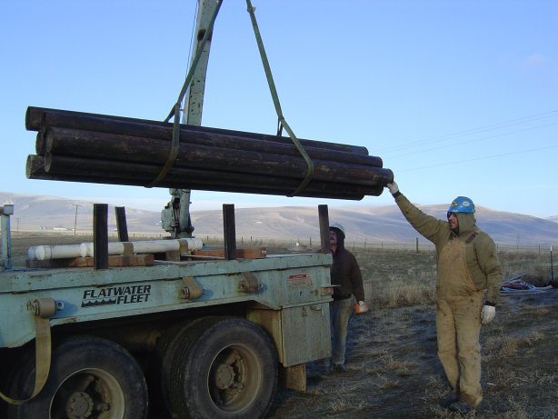 February 2004 Loading additional steel casing for the day's drilling work. Equipment storage and staging is about 2 miles southeast of the dam on private property. The landowner is also providing well water for drilling and testing. The Rattlesnake Hills are in the back ground.
