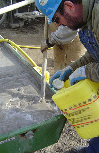 (Right) February 2004 Drill crew mixing polymer drilling fluid (mud) for core drilling. The fluid is used to lubricate the diamond bit and remove soil and rock cutting the the hole while drilling.