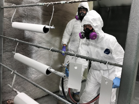Intern applying a protective coating to steel specimens.