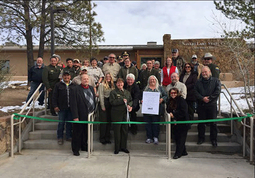 Group celebrating a ribbon cutting for the Visitor Center at Navajo Lake State Park's ceremony 