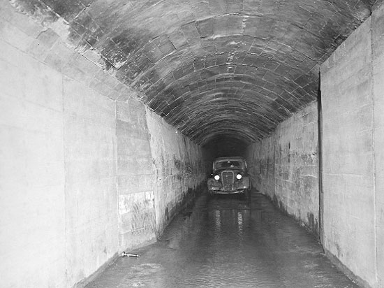 Car shown inside of the Gunnison Tunnel with an inspector’s flashlight on the viewer’s left-hand corner of the tunnel floor in the foreground.